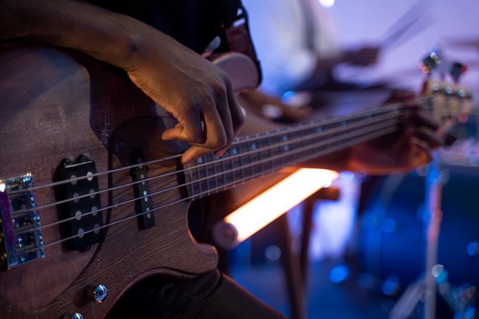 Close-up of a musician strumming an electric bass guitar, showcasing musical expression.